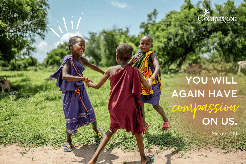 A joyful moment of children dancing, paired with the verse: "You will again have compassion on us." — Micah 7:19.
