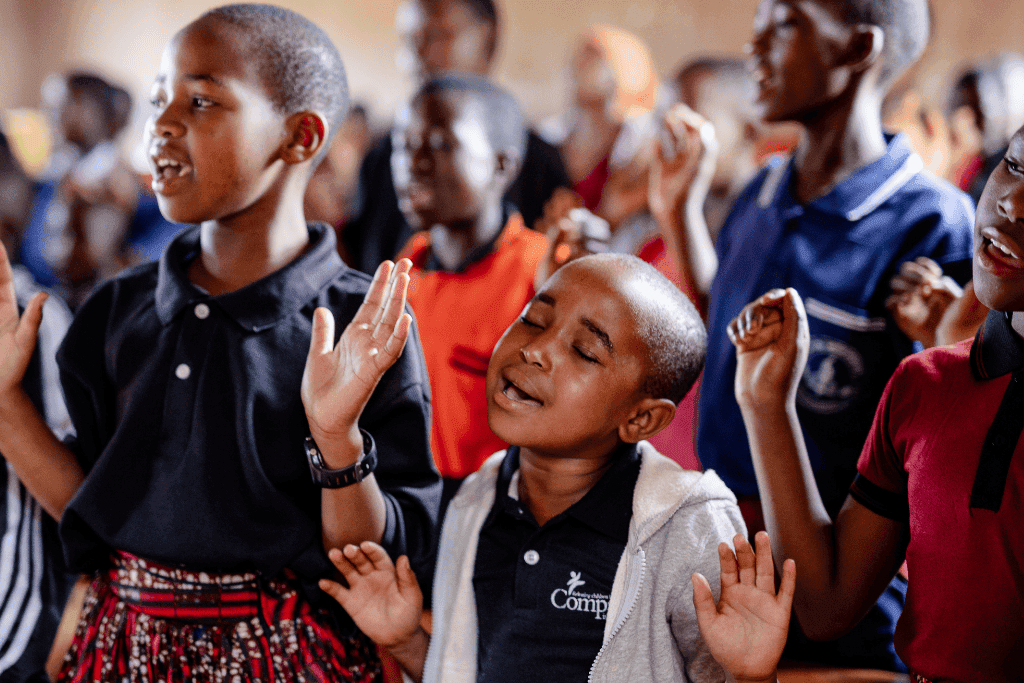 Children sing and worship during prayer at a Compassion project in Tanzania