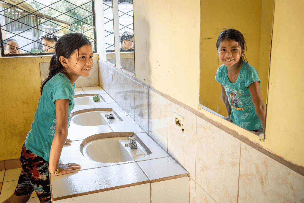 Valeria, 7, Ecuador, smiles at a bathroom mirror.