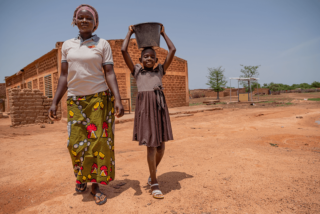 Egodine carries water with her Auntie Nina.