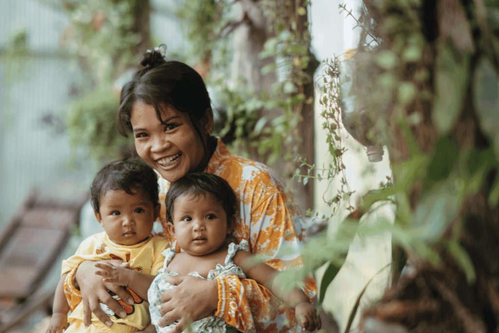 Mum Sereyrath is sitting outside the church with her twins, Rochny and Rochna, on her lap
