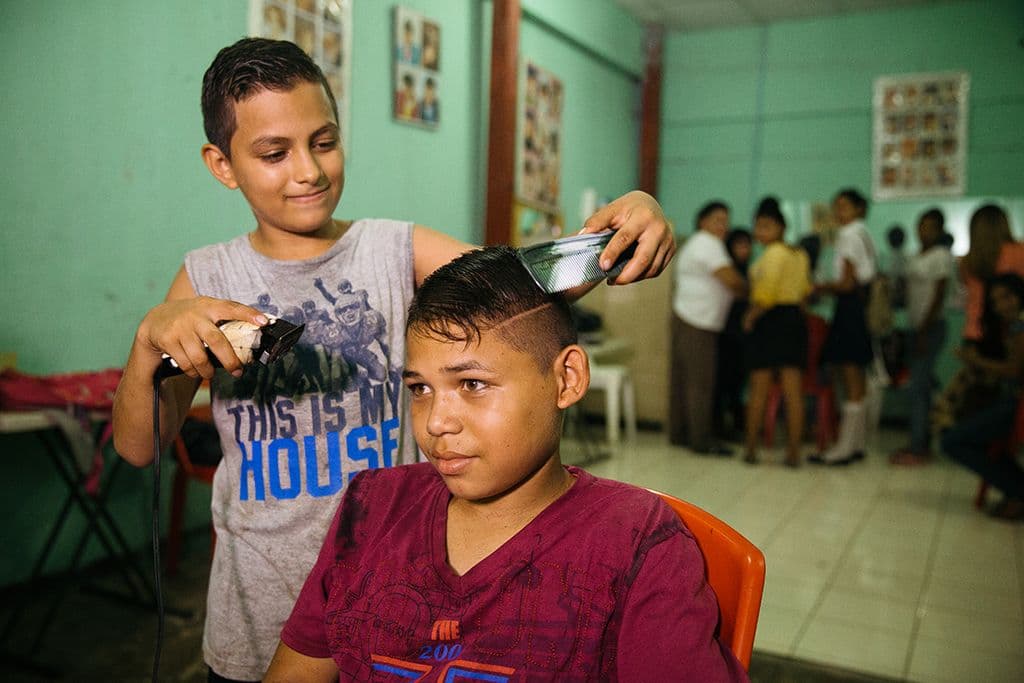 A boy cutting another boys hair