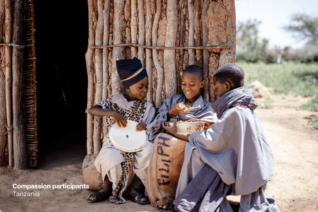 Compassion participants in Tanzania re-enact the Good Samaritan parable. Here, they are pictured eating food together.