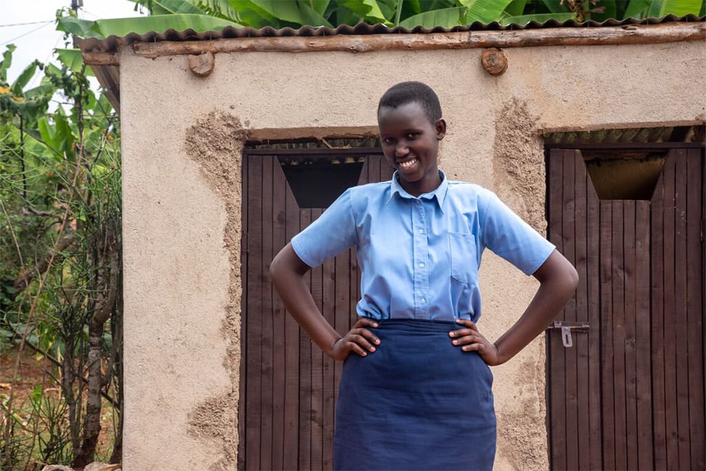 Gloria from Rwanda stood outside her new toilet.