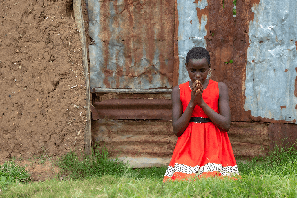 Lynet prays outside her home.