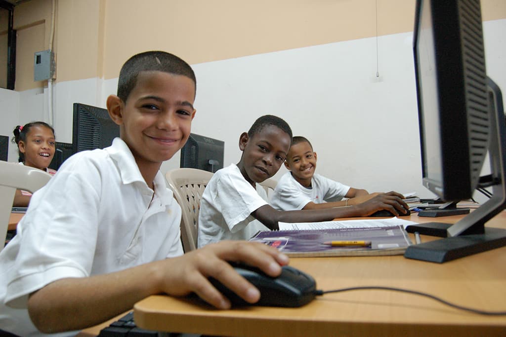 Boys and girls working at computers in the classroom.