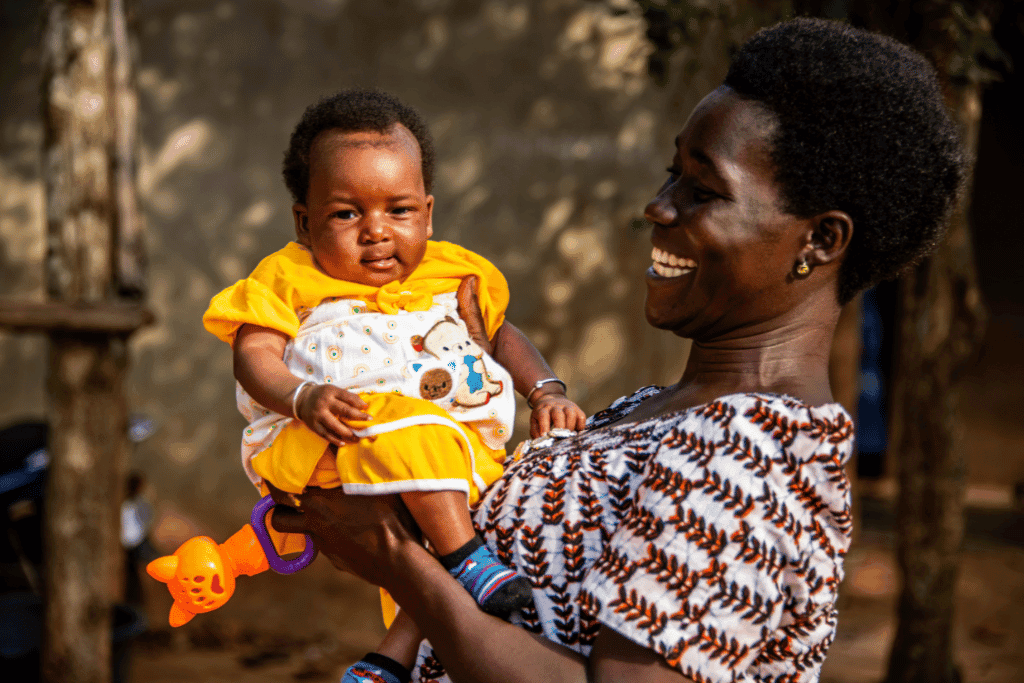 Adjowa is outside happily holding and looking at her baby, Eyram.
